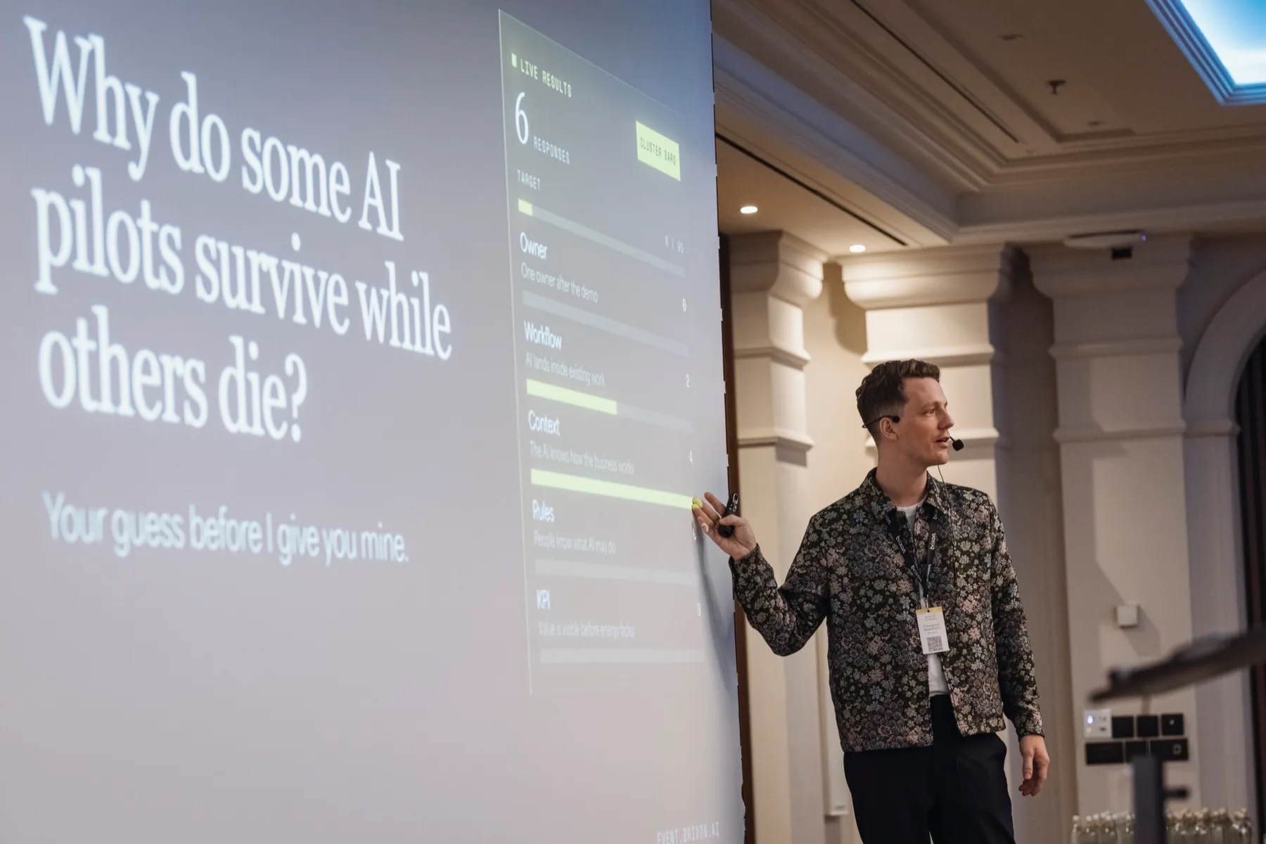 Christoph Sauerborn on stage at the Brixon AI event, slide reading: Why do some AI pilots survive while others die?